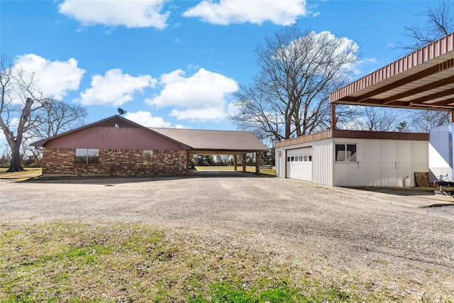 view of side of home with a garage, an outbuilding, gravel driveway, and a carport