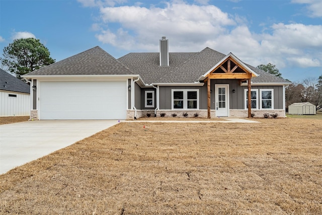 view of front of home featuring an attached garage, a shingled roof, concrete driveway, a chimney, and a front yard