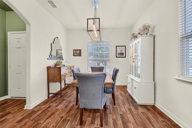 dining room with a healthy amount of sunlight, dark wood-style floors, visible vents, and arched walkways