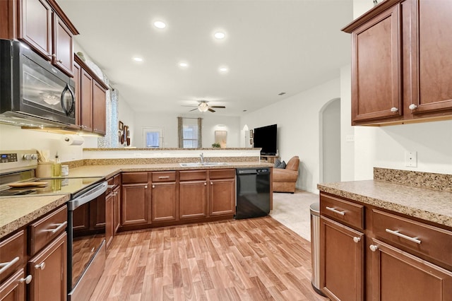 kitchen with a peninsula, black appliances, light countertops, and a sink