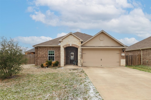 view of front of property with brick siding, concrete driveway, an attached garage, fence, and stone siding