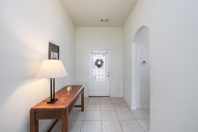 foyer featuring arched walkways, light tile patterned flooring, visible vents, and baseboards