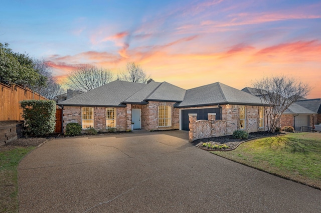 view of front of house featuring a front lawn, fence, concrete driveway, an attached garage, and a shingled roof