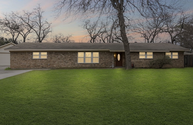 single story home featuring brick siding and a lawn