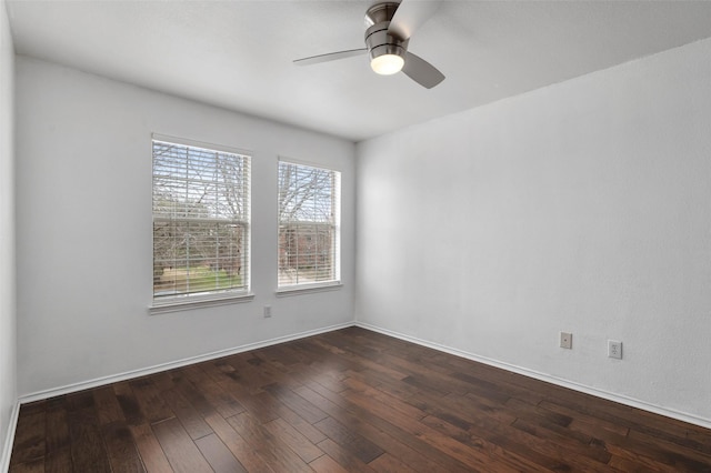 unfurnished room with dark wood finished floors, a ceiling fan, and baseboards