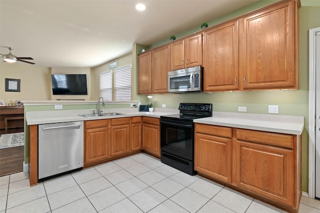 kitchen featuring stainless steel appliances, a sink, open floor plan, light countertops, and brown cabinetry