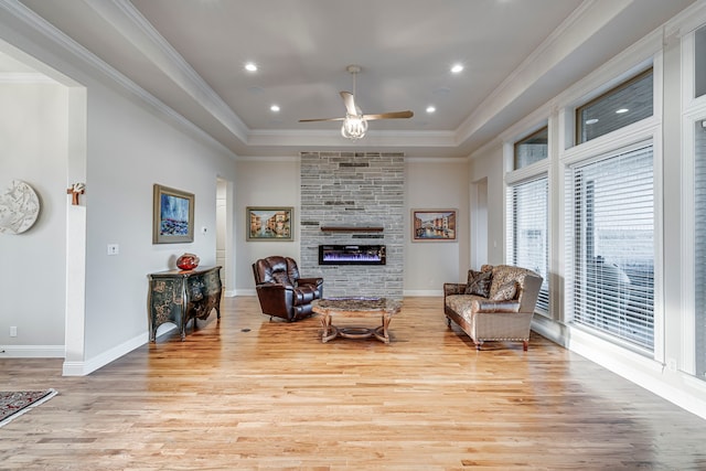 living area featuring light wood-type flooring, a large fireplace, and crown molding