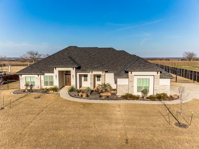 view of front of home with a front lawn, roof with shingles, and fence