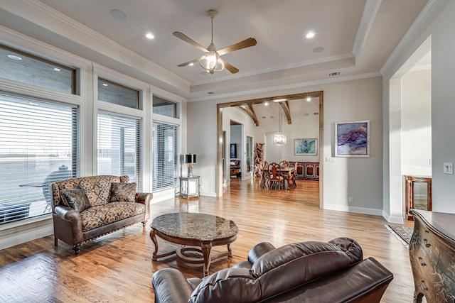 living area featuring visible vents, baseboards, a ceiling fan, crown molding, and light wood-style floors