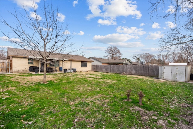 view of yard featuring a fenced backyard, a storage unit, a patio, and an outdoor structure