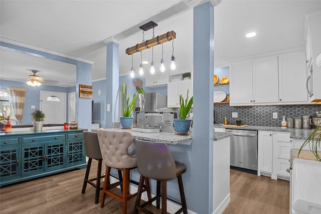 kitchen with pendant lighting, a breakfast bar, stainless steel appliances, white cabinetry, and open shelves