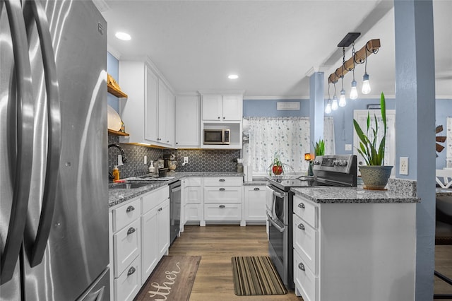 kitchen featuring stone countertops, a sink, white cabinets, hanging light fixtures, and appliances with stainless steel finishes