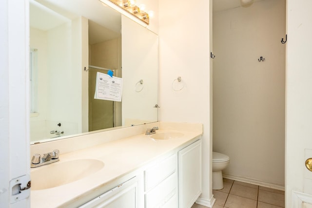 bathroom featuring toilet, double vanity, a sink, and tile patterned floors