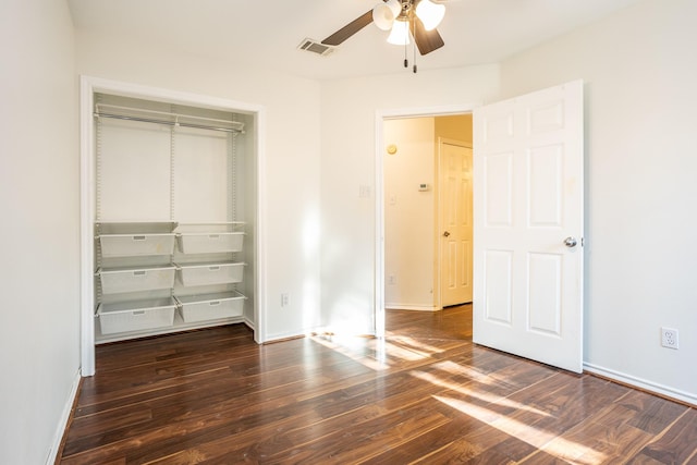 unfurnished bedroom featuring baseboards, visible vents, dark wood-style floors, ceiling fan, and a closet