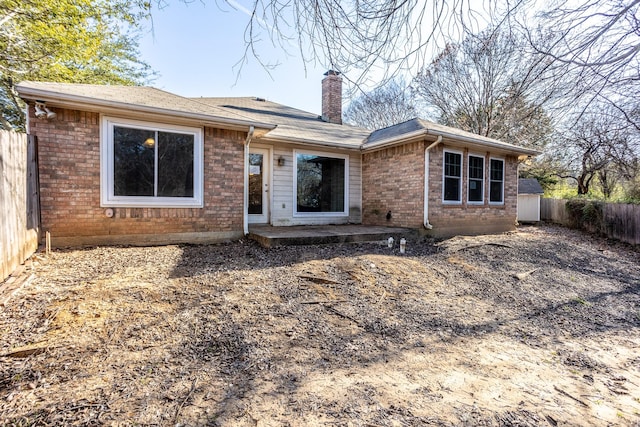 view of front of house featuring a chimney, fence, and brick siding