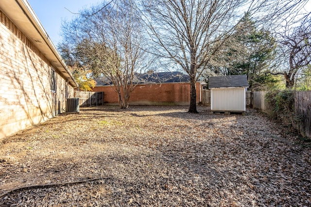 view of yard with an outbuilding, a shed, a fenced backyard, and central air condition unit