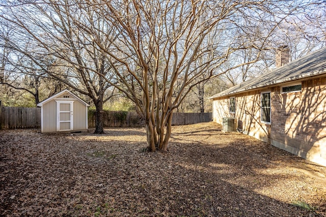 view of yard featuring a storage shed, a fenced backyard, central AC unit, and an outdoor structure