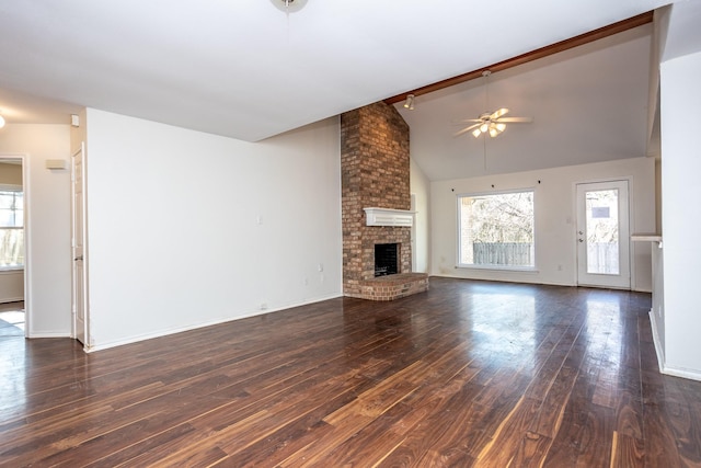 unfurnished living room with dark wood-type flooring, a brick fireplace, beam ceiling, and a healthy amount of sunlight