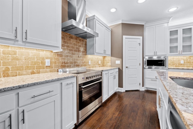 kitchen with white cabinets, wall chimney exhaust hood, glass insert cabinets, light stone counters, and stainless steel appliances