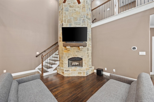 living room with a fireplace, a high ceiling, wood finished floors, baseboards, and stairs