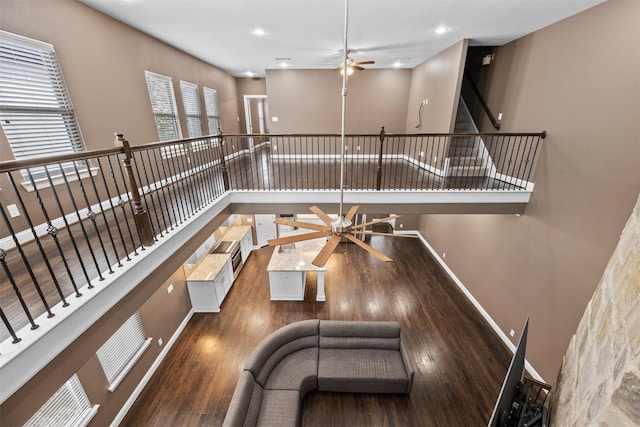 interior space with recessed lighting, a high ceiling, a ceiling fan, baseboards, and dark wood finished floors