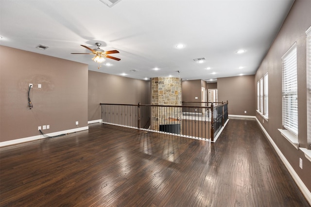 empty room featuring dark wood-style floors, recessed lighting, visible vents, and baseboards