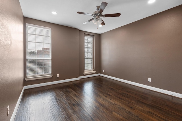 spare room featuring dark wood-style floors, baseboards, and a ceiling fan