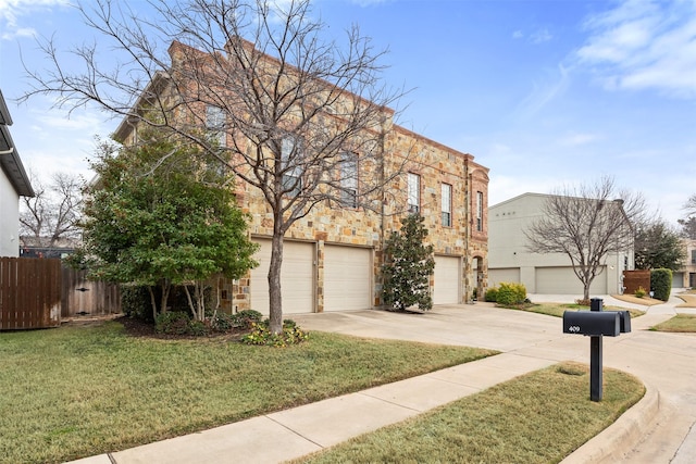 view of front of house featuring concrete driveway, stone siding, an attached garage, fence, and a front yard