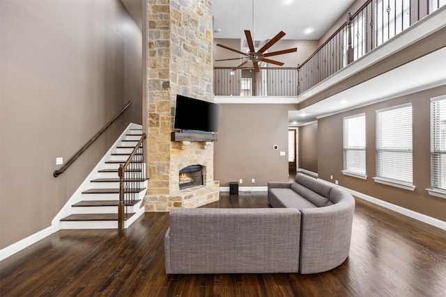 living area featuring a fireplace, wood finished floors, a ceiling fan, and baseboards