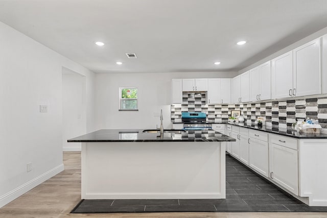 kitchen featuring dark countertops, white cabinets, stainless steel electric range oven, and visible vents