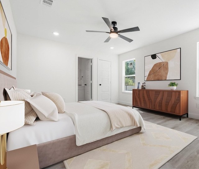 bedroom with baseboards, recessed lighting, ensuite bath, and light wood-style floors