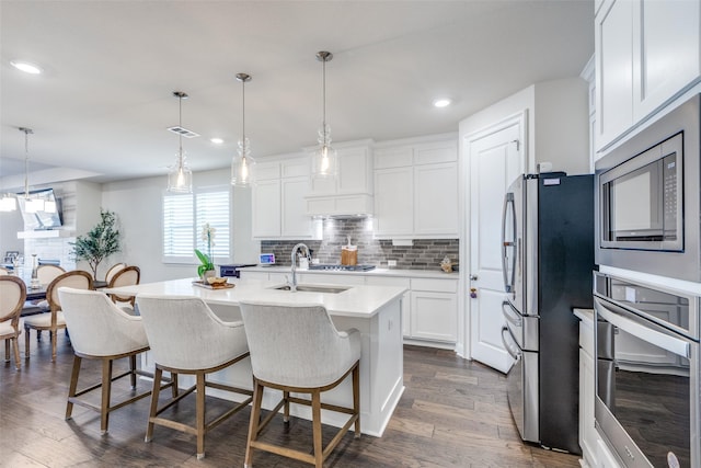 kitchen featuring decorative backsplash, dark wood-style floors, appliances with stainless steel finishes, light countertops, and a sink