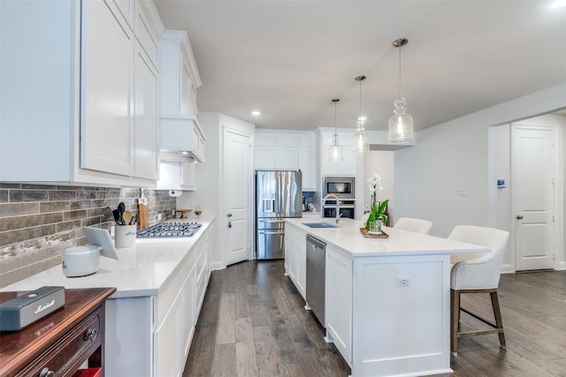 kitchen with appliances with stainless steel finishes, a breakfast bar, dark wood-style flooring, and a sink