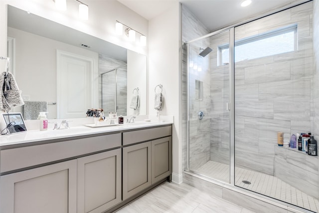 full bathroom featuring double vanity, a stall shower, and a sink