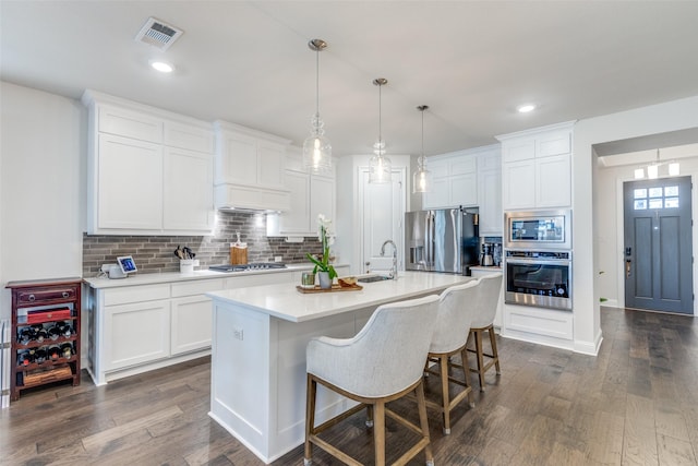 kitchen featuring stainless steel appliances, a sink, visible vents, light countertops, and dark wood finished floors