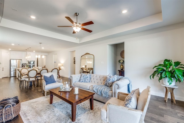 living room featuring baseboards, a raised ceiling, wood finished floors, and recessed lighting