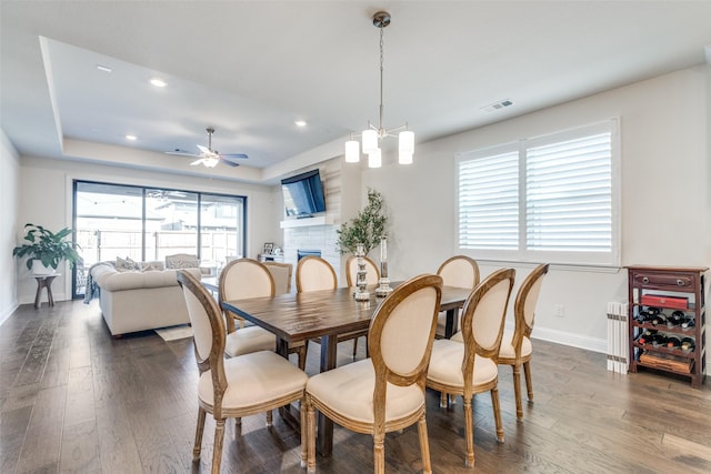 dining space with a fireplace, dark wood finished floors, visible vents, and baseboards