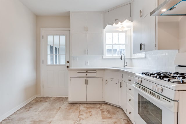 kitchen with white gas stove, under cabinet range hood, a sink, and backsplash