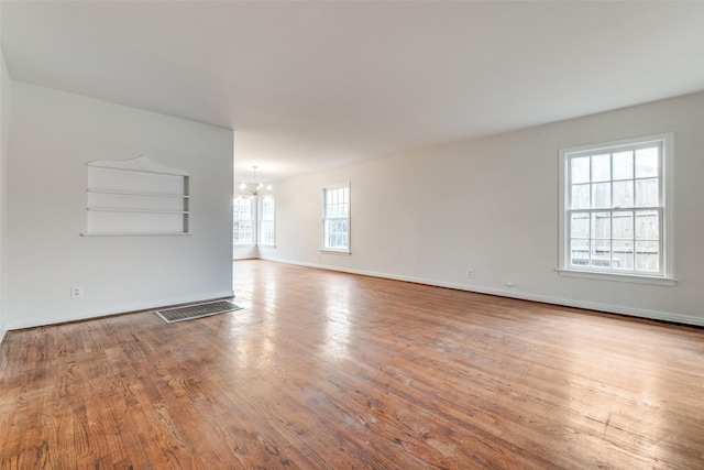 interior space featuring baseboards, wood finished floors, a notable chandelier, and visible vents