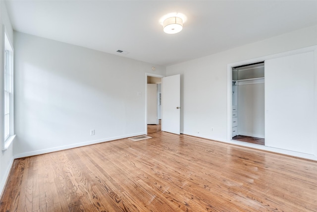 unfurnished bedroom featuring visible vents, baseboards, a closet, and wood finished floors