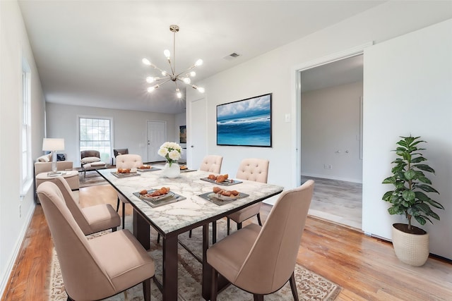 dining area with visible vents, baseboards, a notable chandelier, and light wood-style floors