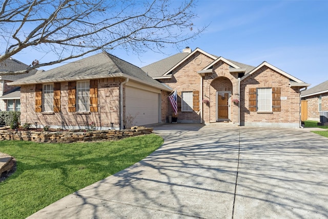 ranch-style home featuring brick siding, a chimney, a garage, driveway, and a front lawn