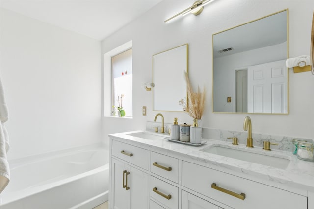 bathroom with double vanity, visible vents, a sink, and a bath