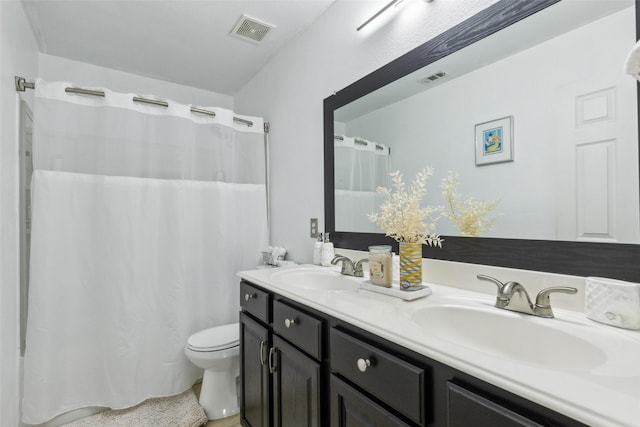 bathroom with visible vents, a sink, toilet, and double vanity