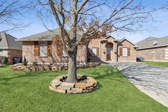 view of front facade with a front yard, brick siding, and central AC unit