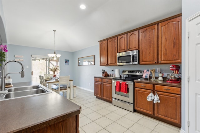 kitchen featuring pendant lighting, stainless steel appliances, dark countertops, lofted ceiling, and a sink