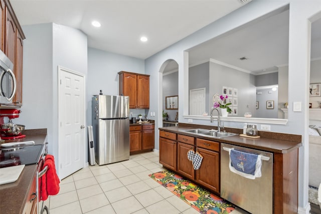 kitchen with stainless steel appliances, dark countertops, ornamental molding, light tile patterned flooring, and a sink