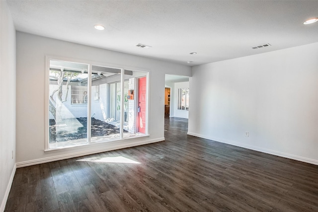 empty room featuring baseboards, visible vents, and dark wood-style flooring