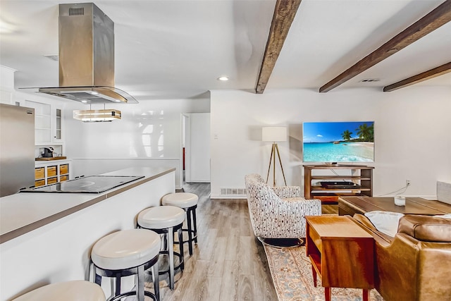 kitchen with light wood finished floors, island range hood, white cabinets, beamed ceiling, and black electric cooktop