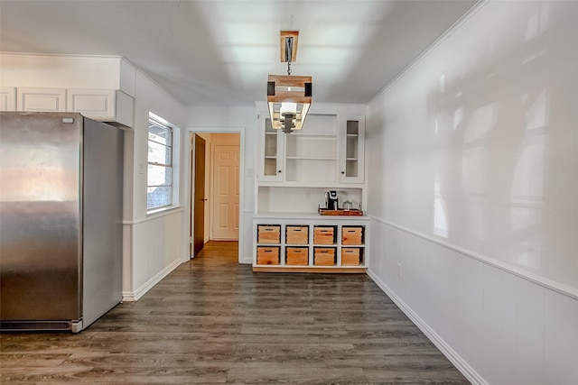 dining area featuring dark wood-type flooring, wainscoting, and crown molding